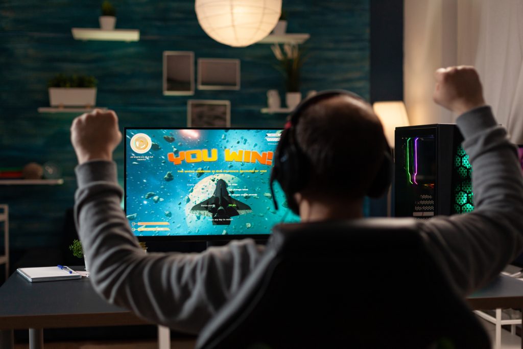 Man raising hands after winning video games on computer